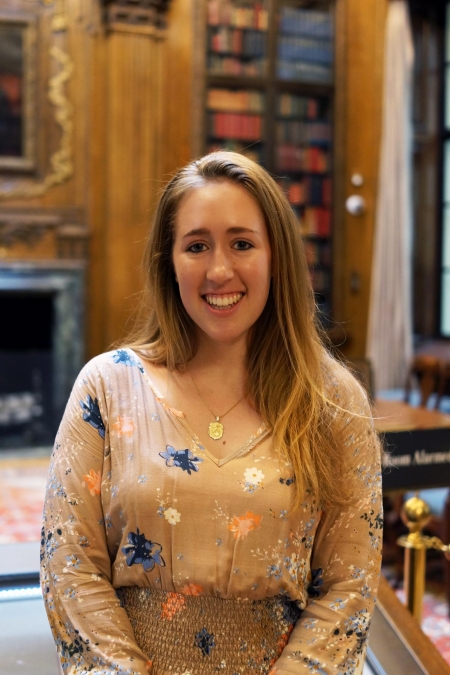 Alana Davitt stands in Widener Library and smiles at the camera