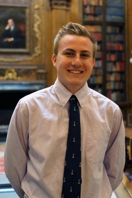 Gavin Moulton stands in Widener Library and smiles at the camera