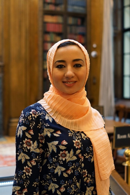 Hanaa Masalmeh stands in Widener Library and smiles at the camera