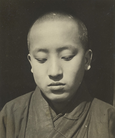 Buddhist nun with closely shaven head looking down