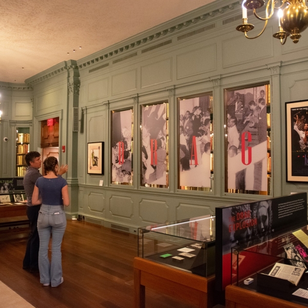Two visitors looking at images on the wall at the American Drag exhibit