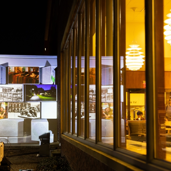 The outside of Lamont Library with a display of photographs projected on the wall