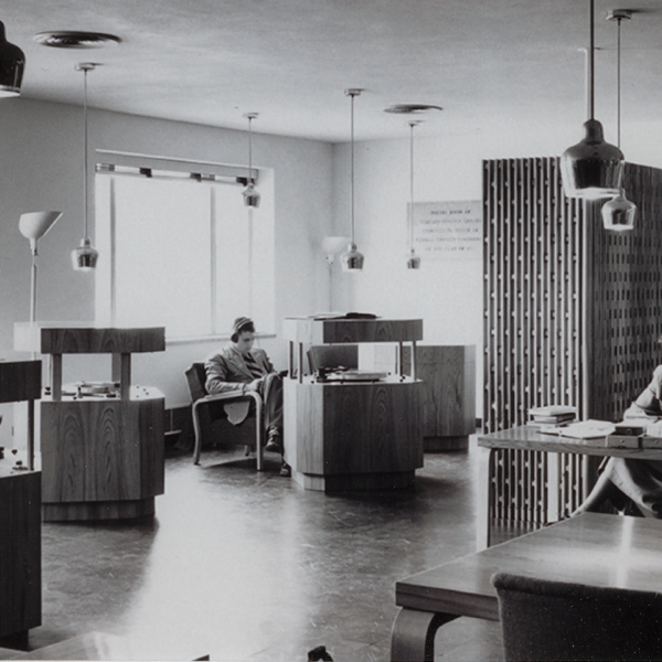 A black and white photograph of a room with desks and chairs