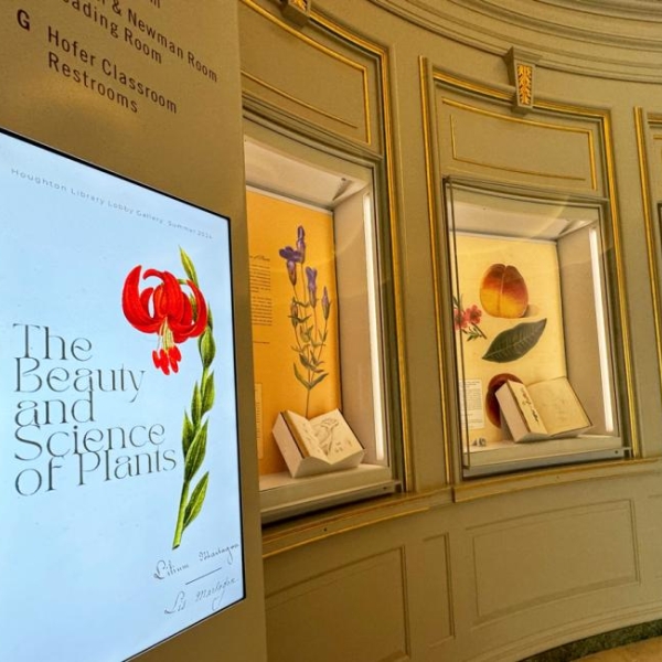 books open and on display in cases, with in the foreground a digital sign with a plant illustration that reads next to it "The Beauty and Science of Plants"