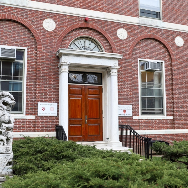 The exterior of the Harvard-Yenching Library building, a red-brick facade with a statue of a dragon out front