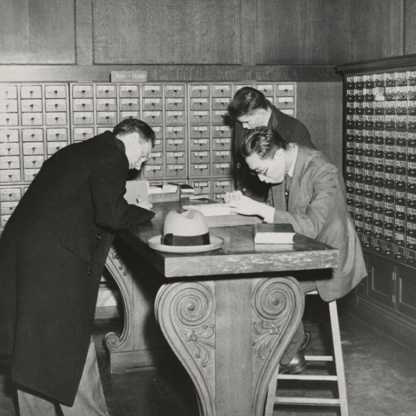 Black and white photograph of three students using card catalogs at Widener Library