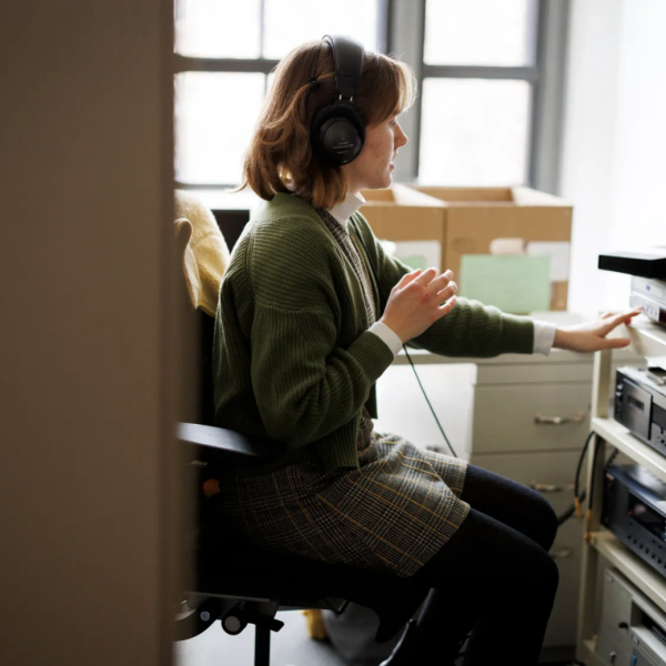 A Harvard Library technician in front of a desktop and a VHS deck, watching a tape.