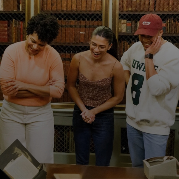 The Hamilton touring cast look at documents in Houghton Library with curator John Overholt.