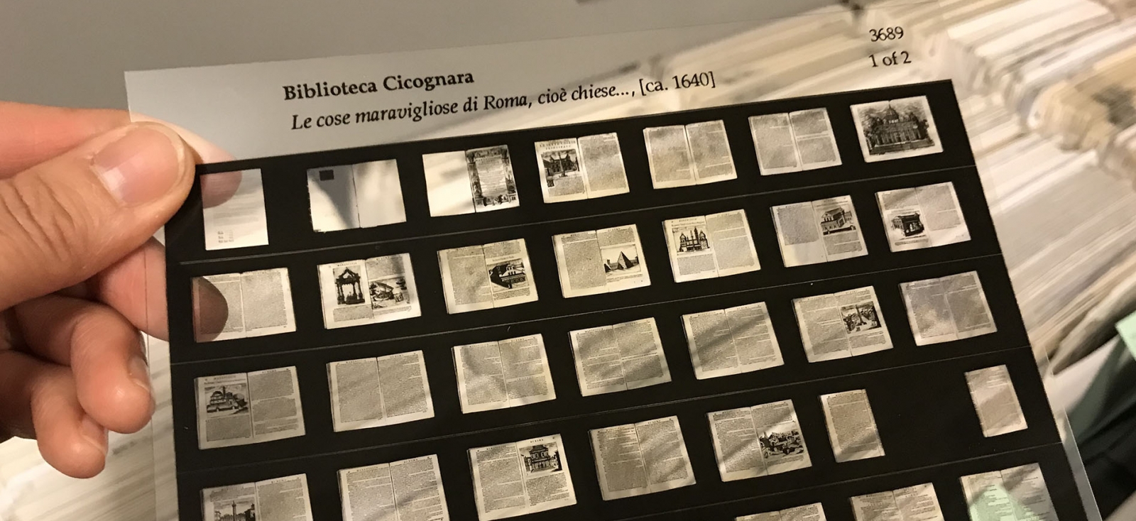 Color photograph showing a hand holding a piece of microfiche from Biblioteca Cicognara, ca 1640 