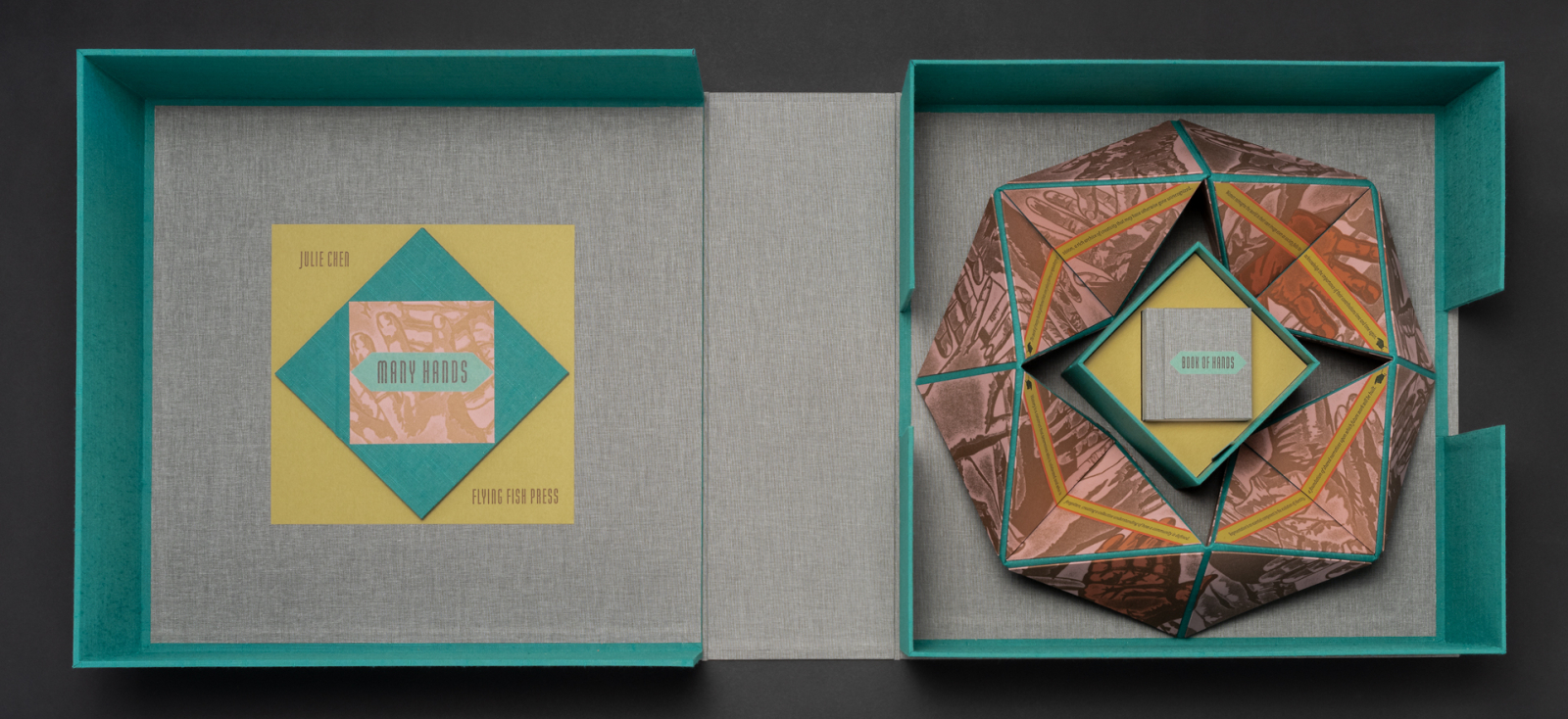 Opened box containing folded paper object with a tiny book titled “Many Hands”