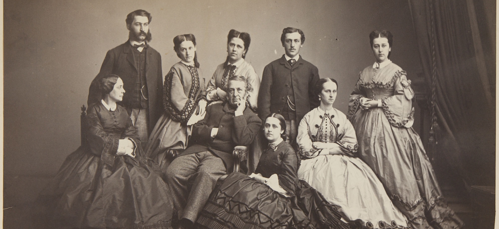 Salted paper print showing nine members of the Hecksher Family: two parents and seven adult children.  The father is seated in the center with his right hand tucked into his jacket, left arm resting on the arm of the chair and left hand gently raising to his chin. His wife is seated to his left looking at him. Standing behind them and facing front are, from left to right, a bearded son, two daughters, another son, and a daughter. Two other daughters are seated in front, one kneeling by the father. 