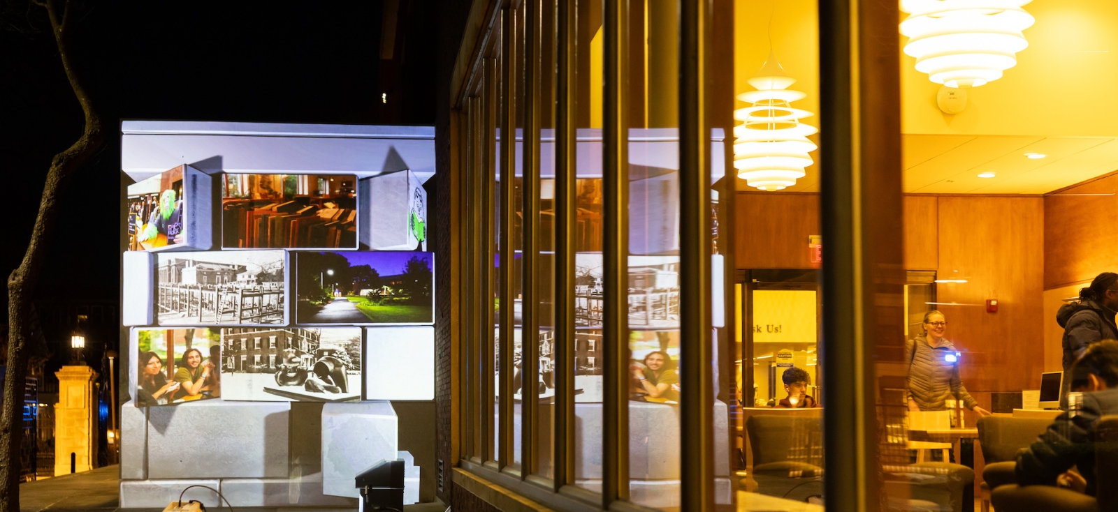 The outside of Lamont Library with a display of photographs projected on the wall
