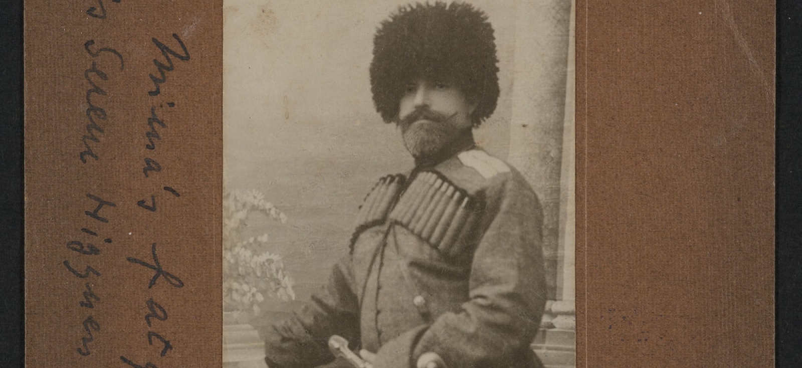 Bearded man in traditional Georgian dress: chokha coat, gazyr, papakha hat, and a sword at his belt.