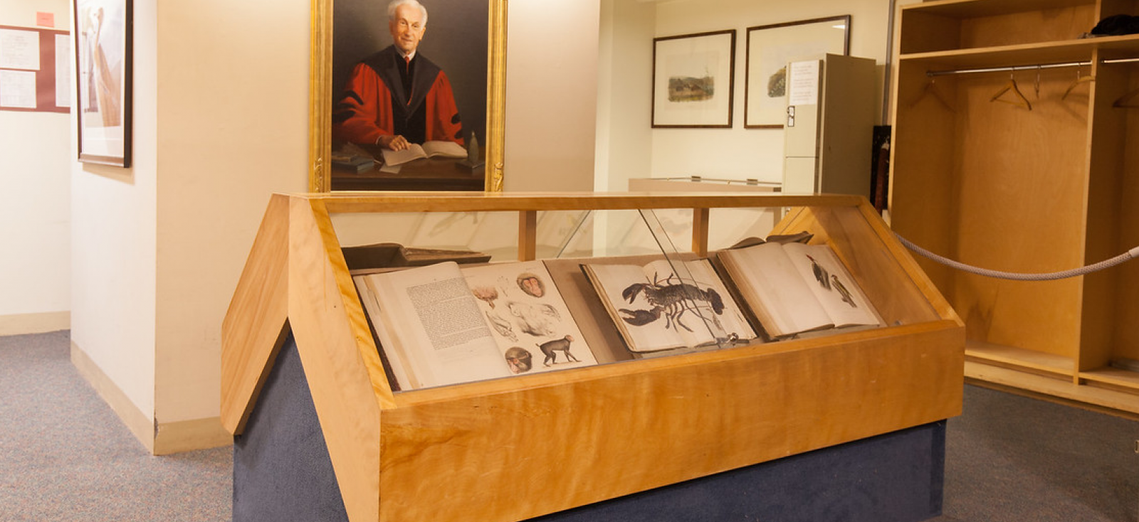 Room with portrait of an older man and large books with scientific photos of animals.