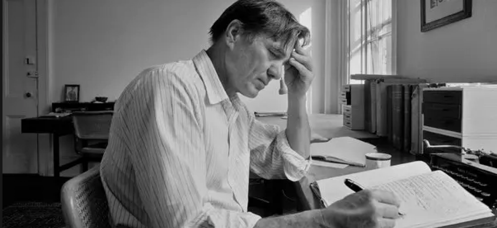 black and white photograph of a man writing at a desk