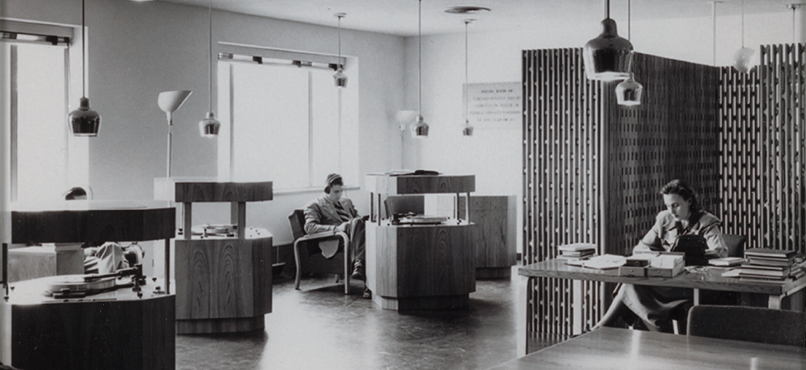 A black and white photograph of a room with desks and chairs