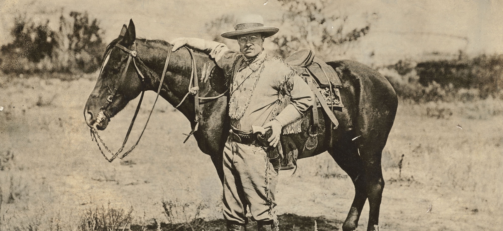 Teddy Roosevelt stands next to a horse in North Dakota in 1885.