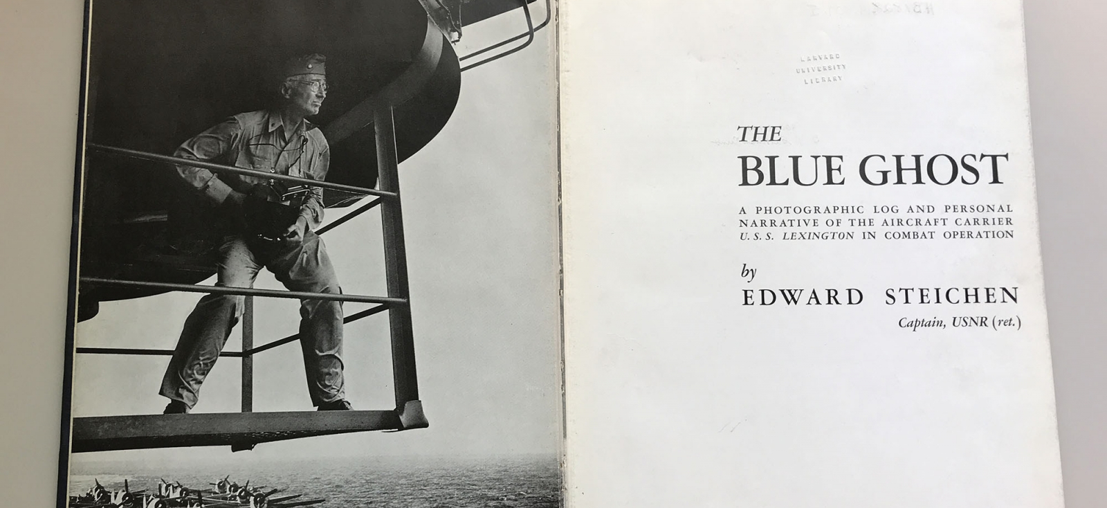 Title page of 1st edition of “The Blue Ghost: A photographic log and personal narrative of the aircraft carrier U.S.S. Lexington in combat operation by Edward Steichen, Captain, USNR (ret.)” and frontispiece with a photograph of Edward Steichen in uniform with camera strung around his neck standing above the flight deck with planes below. 