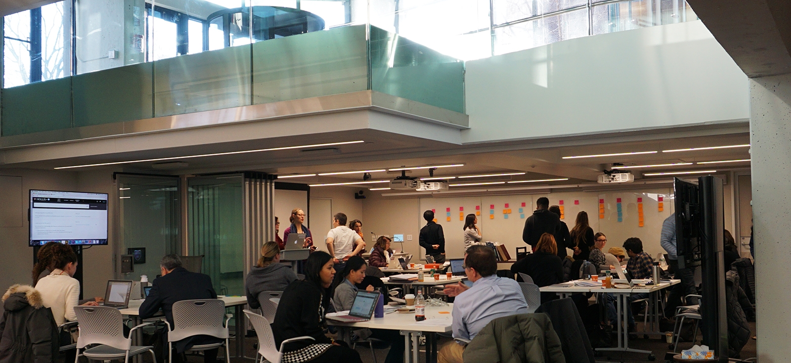 Unabridged participants sit around tables in the Cabot Library during a session. 