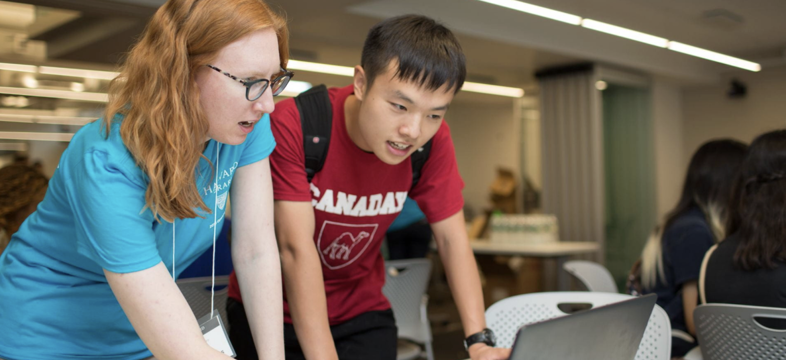A library staff guides a patron through the different library services, with an open laptop in front of them.