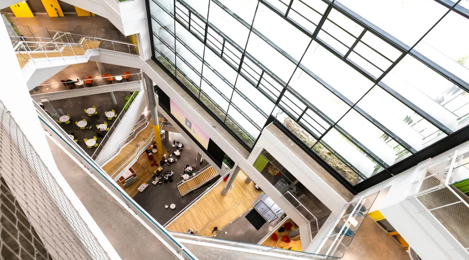 The interior of a building is seen with large windows and open spaces looking through several floors 