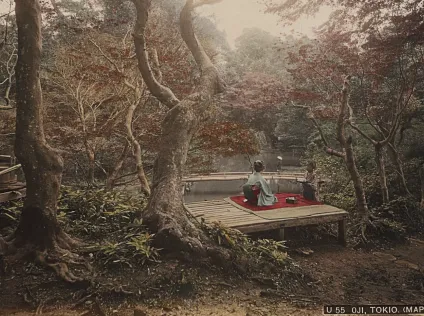 A woman in a kimono sits in a Japanese garden, as another stands before her.