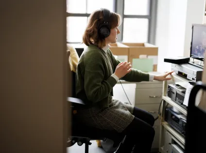 A Harvard Library technician in front of a desktop and a VHS deck, watching a tape.