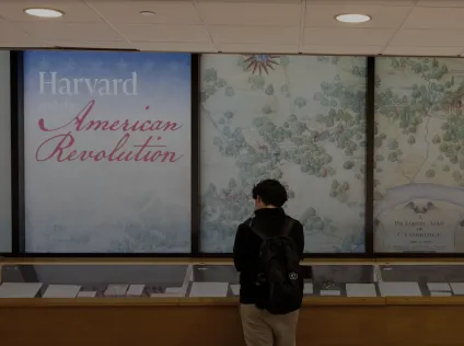 A person checks out the Harvard and the American Revolution exhibit at Pusey Library.