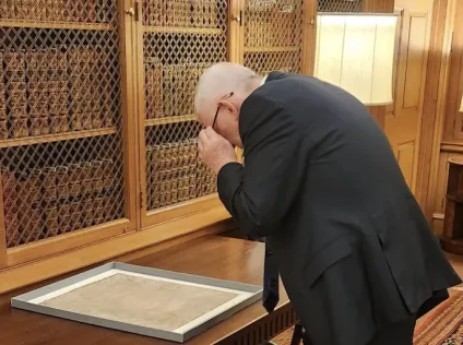 Speaker Hoyle bending over to take a good look at the framed Magna Carta at the table in front of him.
