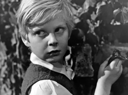 A black and image image of a young boy looking over his shoulder at the viewer.