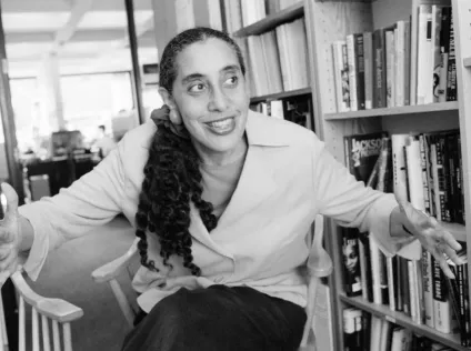A black and white photo of Lani Guinier surround by books.