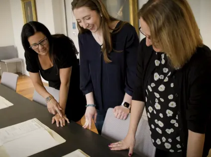 Kristen Kelly, Serene Williams, and a former student of theirs look at materials on a table at Schlesinger Library.