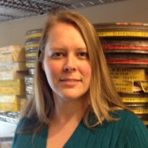 Headshot of Danielle Adams, posed against a shelf of film canisters