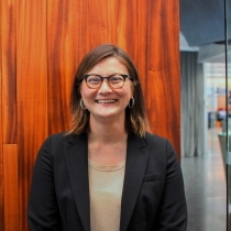 Rebecca Martin standing inside Cabot Library against at wooden backdrop.