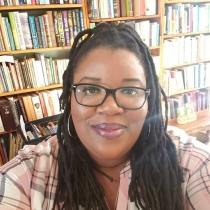 Jamillah is in the foreground with a shelves of books in the background.