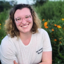 A white, nonbinary individual with dark hair and bleached roots.