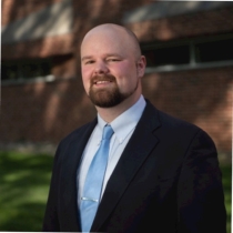 handsome bearded bald man wearing a suit with a tie clip