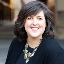 White woman with brown hair, wearing a black blazer