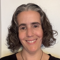 person with dark curly hair and dark eyes