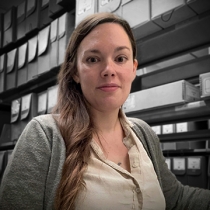 Emily Atkins in front of shelves with archival boxes.