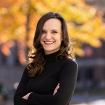 Woman with brown hair and black shirt against a fall background