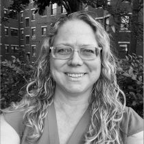 Black and white photo of white woman with glasses and light-colored, long, wavy hair