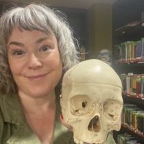 woman with gray hair holding a human skull