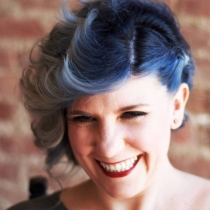 Woman with short blue hair smiling.