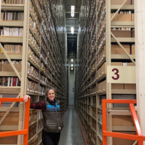 Woman standing between huge bookshelves