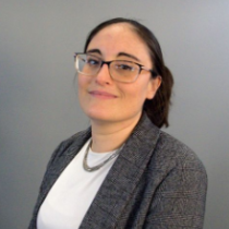 Alita Bombaci headshot, woman with brown hair wearing glasses looking at camera. 