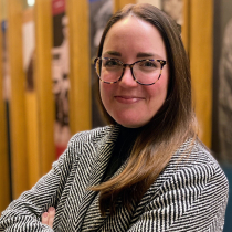Woman in glasses with arms crossed.