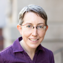 Amanda Hope, a white woman with short, graying brown hair, wearing red glasses and a purple button-down shirt.
